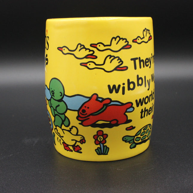 Yellow mug with colorful illustrations and text on a dark background