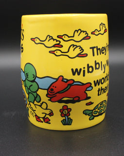 Yellow mug with colorful illustrations and text on a dark background