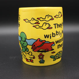 Yellow mug with colorful illustrations and text on a dark background