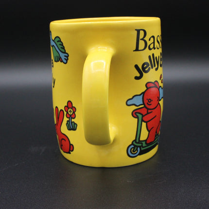 Yellow mug with cartoon characters and text on a black background