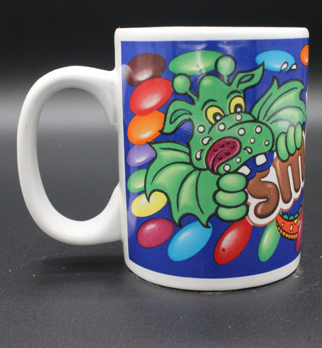 Colorful mug with a cartoon dragon design on a dark background
