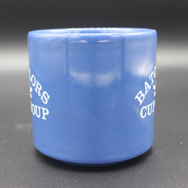 Blue ceramic cup with white text on a dark background