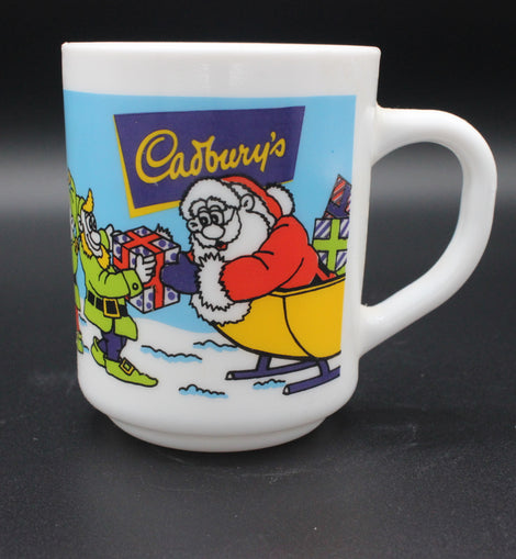 White mug with Cadbury's Christmas-themed design featuring Santa Claus and a reindeer on a black background.