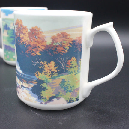 White mug with a scenic design of trees and water on a dark surface