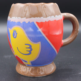Colorful ceramic mug with a cartoon character design on a dark background