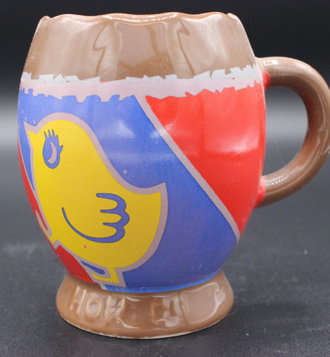 Colorful ceramic mug with a cartoon character design on a dark background