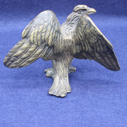 Brass eagle figurine on a blue background