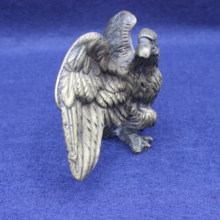 Brass-coloured eagle figurine on a blue background