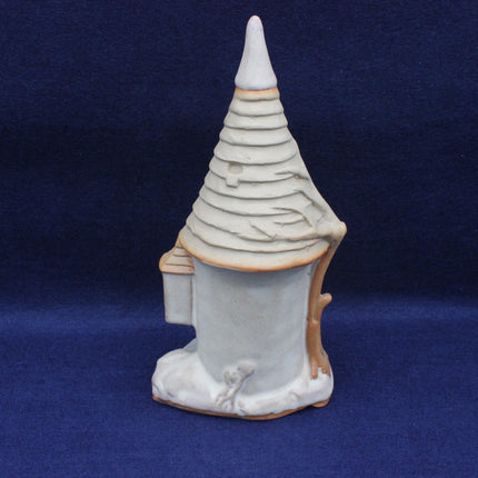 Ceramic sculpture of a tower with a pointed roof on a blue background