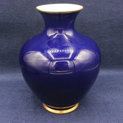 Blue ceramic vase with gold base and rim on a dark blue background