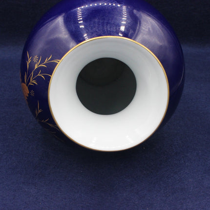 Top view of a blue ceramic vase with white interior and gold floral patterns on a dark blue background