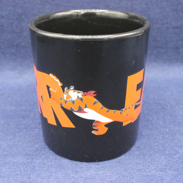 Black mug with orange tiger design on a blue background
