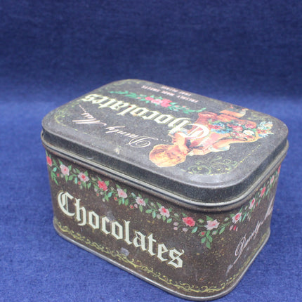 Vintage-style chocolate tin with decorative lid on a blue background