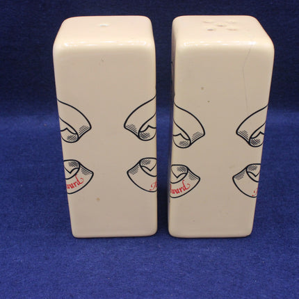 Two white ceramic salt and pepper shakers with black illustrations on a blue background