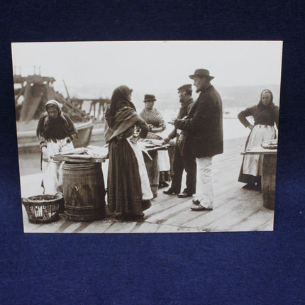 Vintage black and white photo of people on a dock with boats in the background