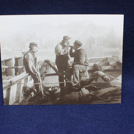 Vintage black and white photo of four men on a boat with a blue background