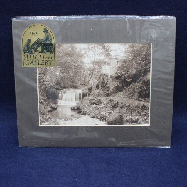 Matted black and white photograph of a waterfall and mill, framed by The Sutcliffe Gallery.