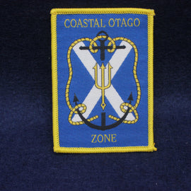 Embroidered patch with 'Coastal Otago Zone' text and nautical symbols on a blue background.