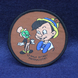 Circular patch with cartoon characters on a brown background, featuring 'Walt Disney Productions'.
