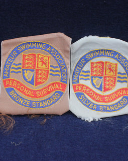 Two embroidered patches from the Amateur Swimming Association on a dark blue background.