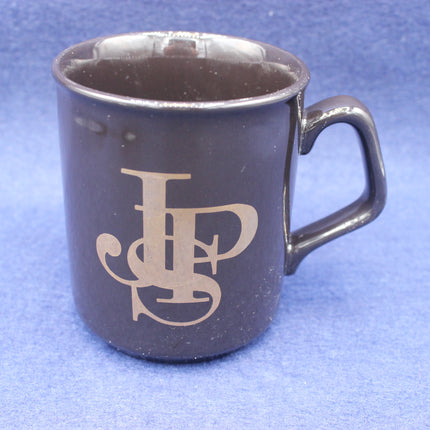 Black mug with a logo on a blue background