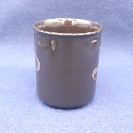 Black ceramic cup with gold lettering on a blue background