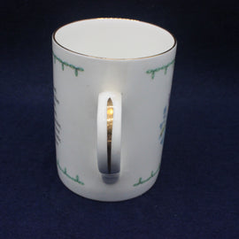 White mug with green text on a dark blue background