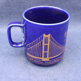 Blue mug with a gold bridge design on a blue background