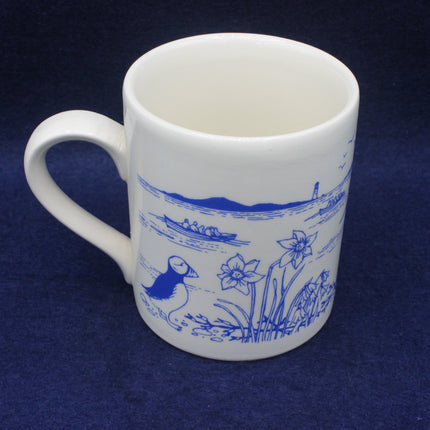 White mug with blue nature-themed design on a dark blue background