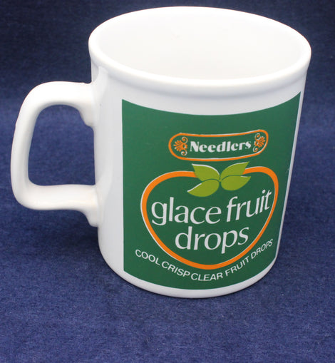 White mug with Needlers glace fruit drops branding on a blue background