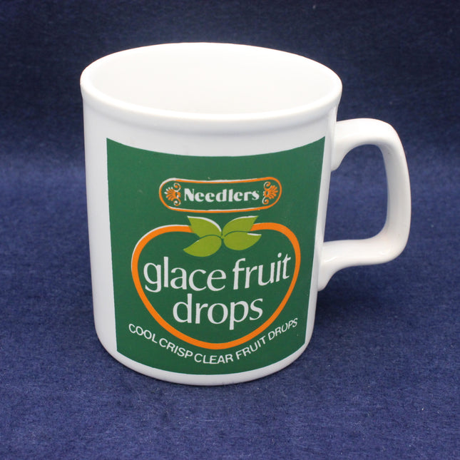 White mug with Needlers glace fruit drops branding on a blue background
