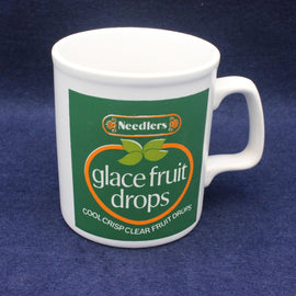 White mug with Needlers glace fruit drops branding on a blue background