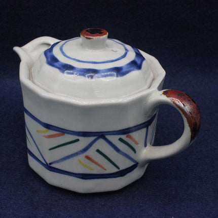 Ceramic teapot with geometric patterns on a dark blue background