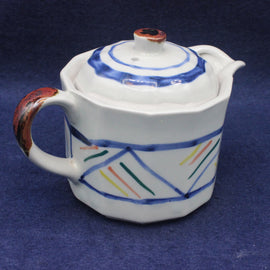 Ceramic teapot with colorful geometric patterns on a blue background