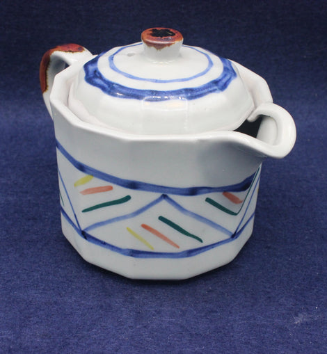 Ceramic tea pot with colorful patterns on a blue background