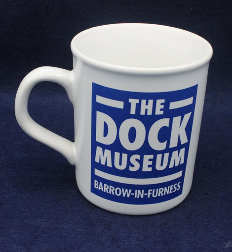 White mug with text 'The Dock Museum Barrow-in-Furness' on a dark blue background