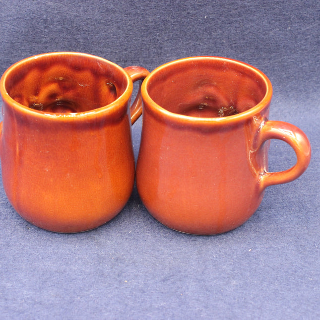 Two brown ceramic mugs on a gray background