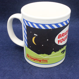 White mug with a cow design and text on a blue background