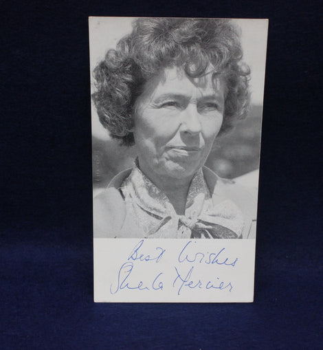 Black and white photo of a woman with curly hair, signed by Sheila Mercier, on a dark background.
