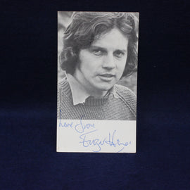 Black and white photo of Frazer Hines with an autograph on a dark background