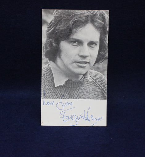 Black and white photo of Frazer Hines with an autograph on a dark background