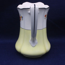 White ceramic pitcher jug with floral designs on a blue background