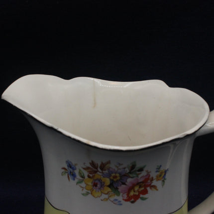 Vintage ceramic pitcher with floral design on a black background