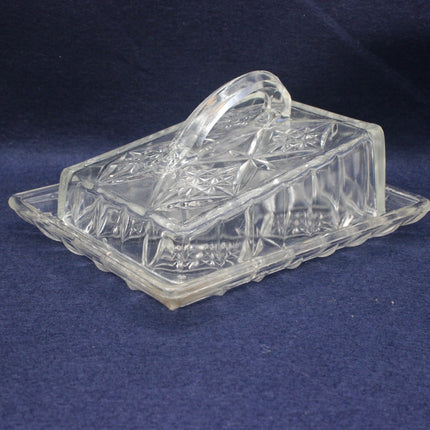 Clear glass butter dish with lid on a dark blue background