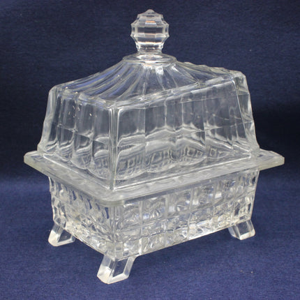 Clear glass lidded butter container on a dark blue background