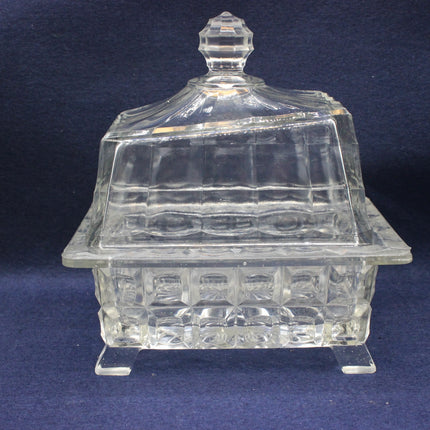 Clear glass candy dish with lid on a dark blue background
