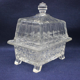 Clear glass covered butter dish on a dark blue background
