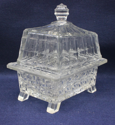 Clear glass covered butter dish on a dark blue background
