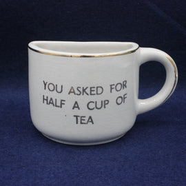 White mug with text 'You asked for half a cup of tea' on a blue background