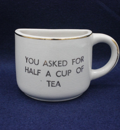 White mug with text 'You asked for half a cup of tea' on a blue background